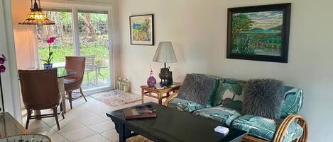 A cozy living room with a glass-top table, a sofa, and a dining area with chairs.
