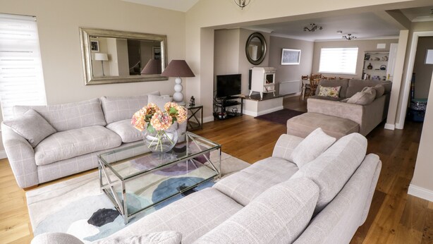 A spacious living room with two grey sofas, a glass coffee table, and a fireplace. - Curragh Hill (Mulranny)