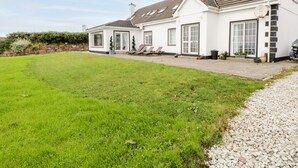 A two-story house with a well-maintained lawn and a patio area. - Curragh Hill (Mulranny)