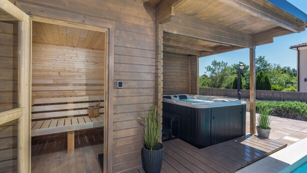 Een houten terras met een jacuzzi en een sauna.