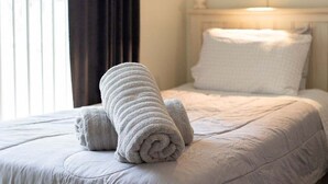 A neatly made bed with rolled towels and a white headboard. - 10 - Beautiful home with Sparkling Pool & Games Room Near Disney Parks (Clermont)
