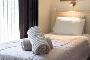Un lit bien fait, avec des serviettes pliées et une tête de lit blanche.