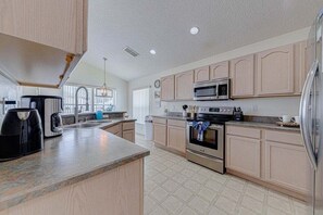 Uma cozinha moderna com armários de madeira clara, eletrodomésticos de aço inoxidável e uma ilha grande.