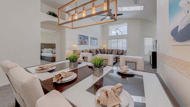 A dining area with a wooden table, chairs, and a hanging light fixture. - 10 - Beautiful home with Sparkling Pool & Games Room Near Disney Parks (Clermont)