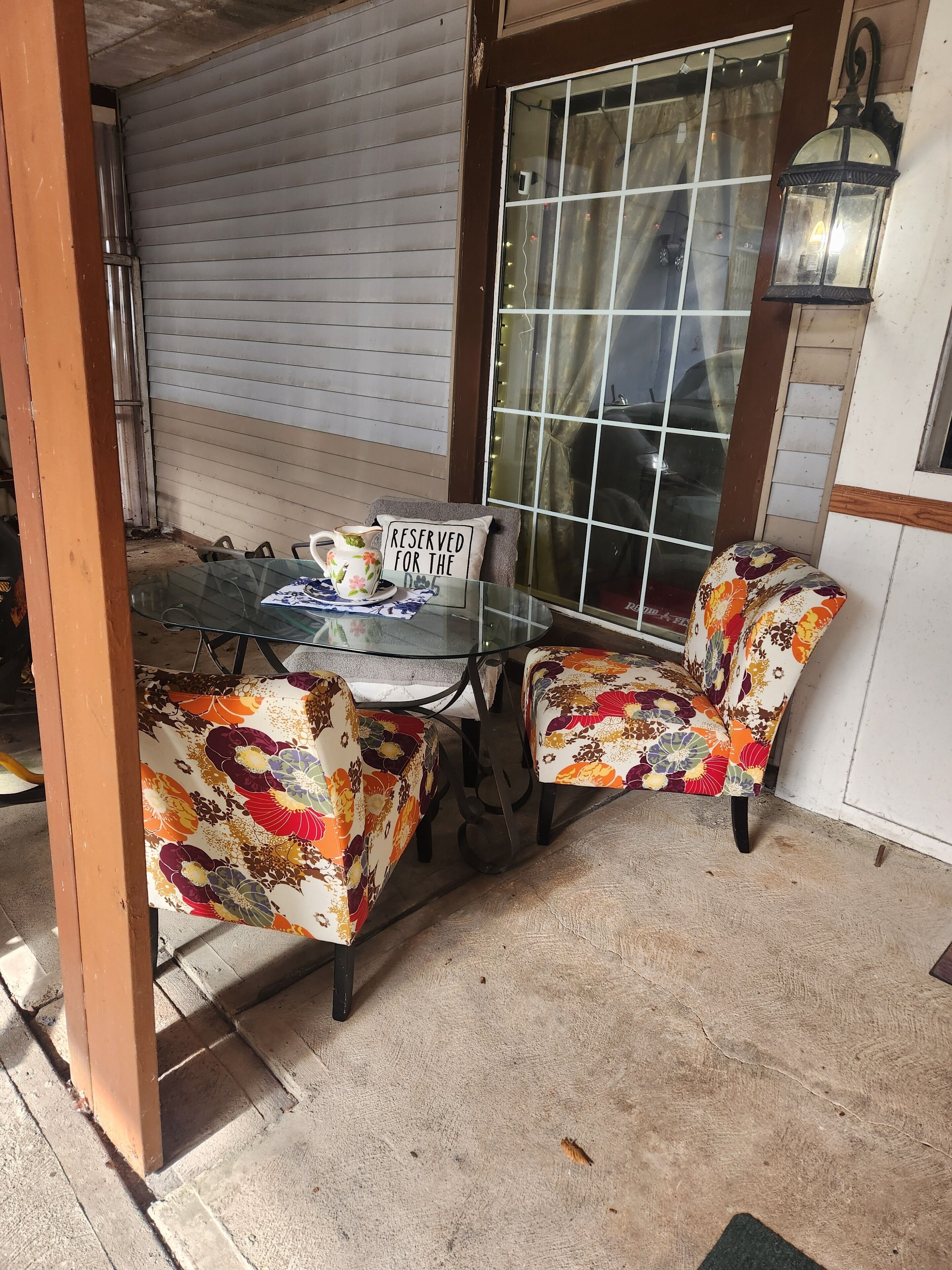 A glass table with chairs, a 'RESERVED FOR THE DAY' sign, and a decorative lantern.