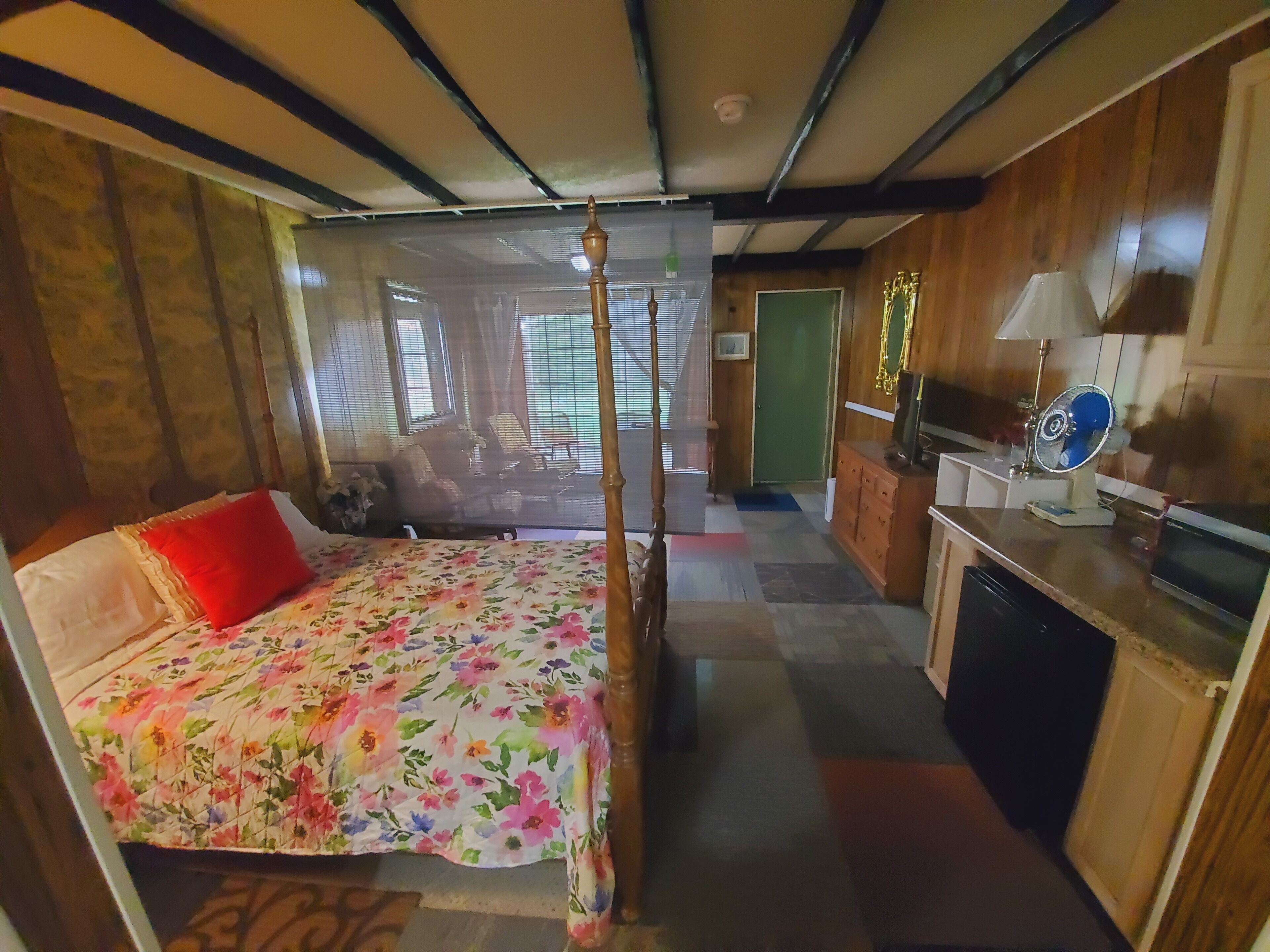 Una habitación con cama con dosel, un escritorio con lámpara y un televisor.