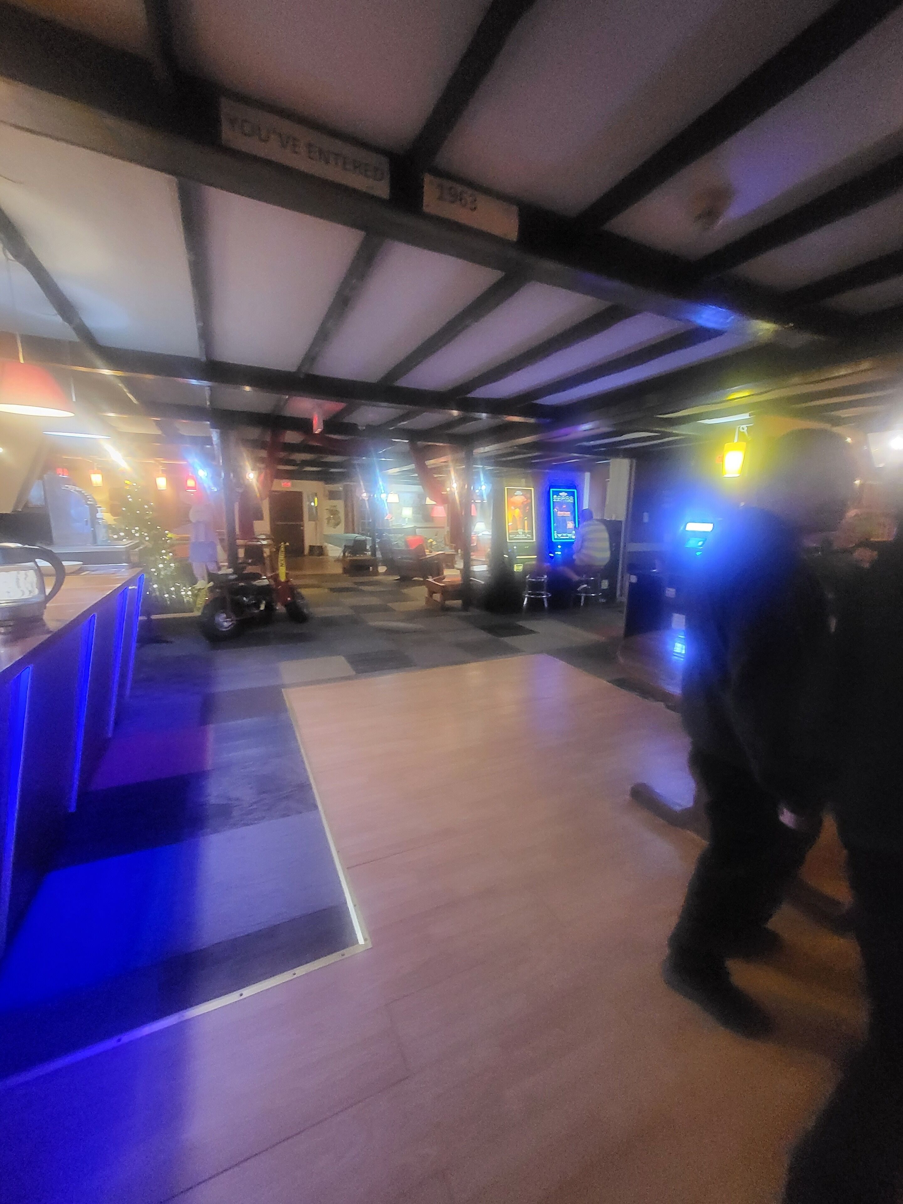A spacious lobby with a check-in counter, a Christmas tree, and a neon-lit arcade area.