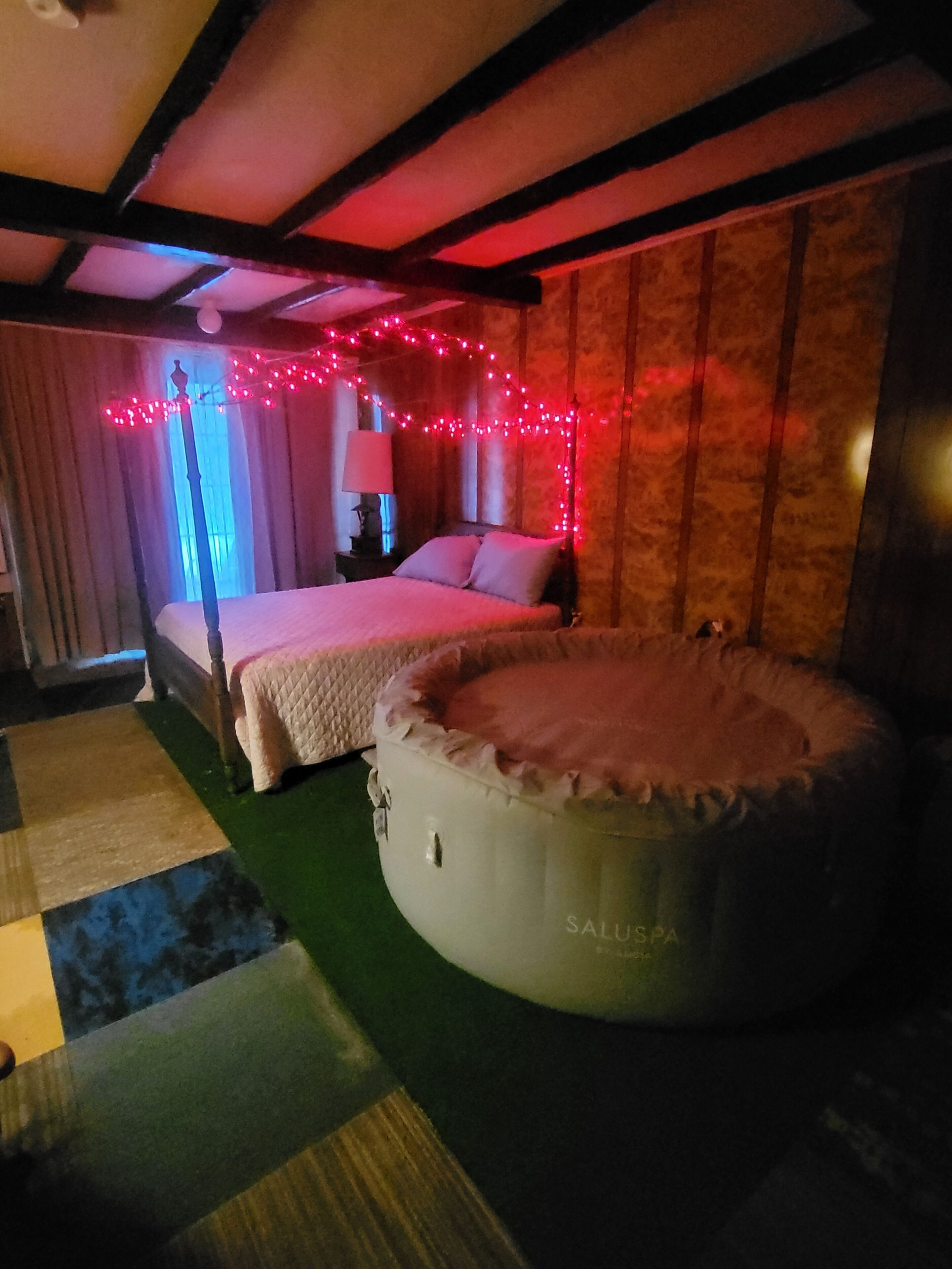 Une chambre à coucher avec un lit, un coin salon circulaire et une fenêtre avec des rideaux.