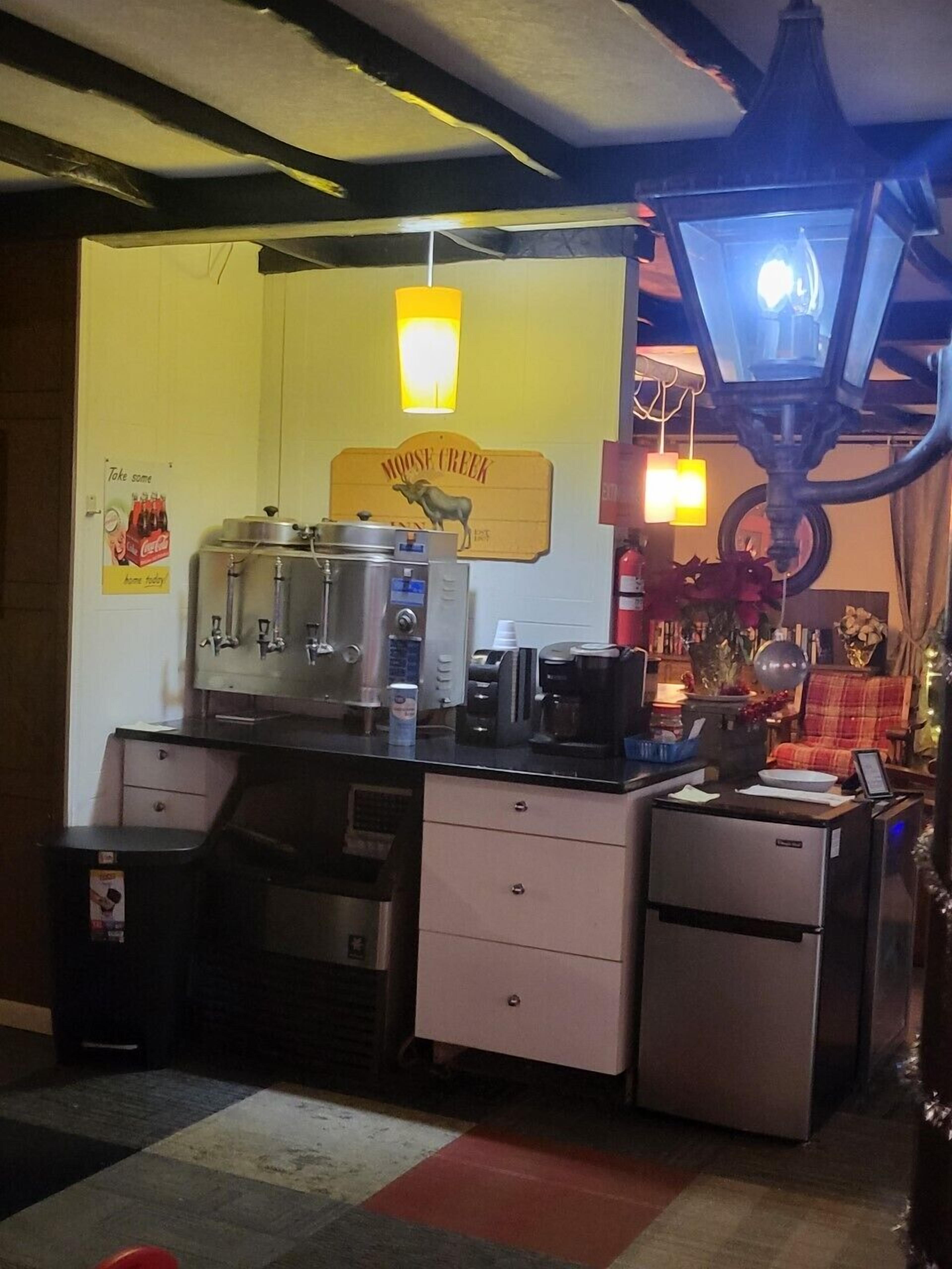 Una cocina compacta con cafetera, refrigerador y encimera con diversos objetos.