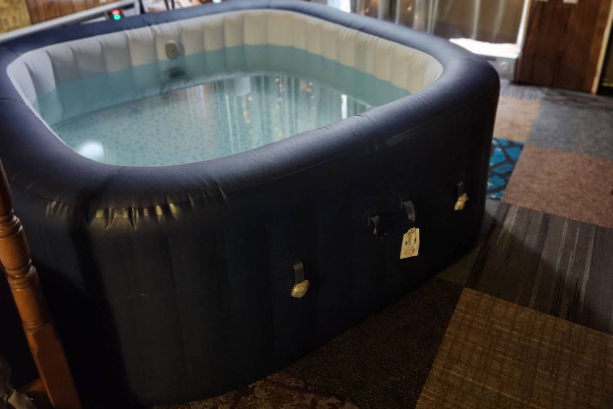 A hot tub in a room with wooden walls and a patterned carpet.