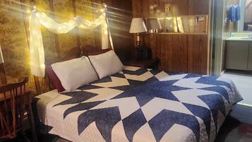 Ein Schlafzimmer mit einem großen Bett, Holzwänden, einem Nachttisch, einem Sessel und einem kleinen Tisch.