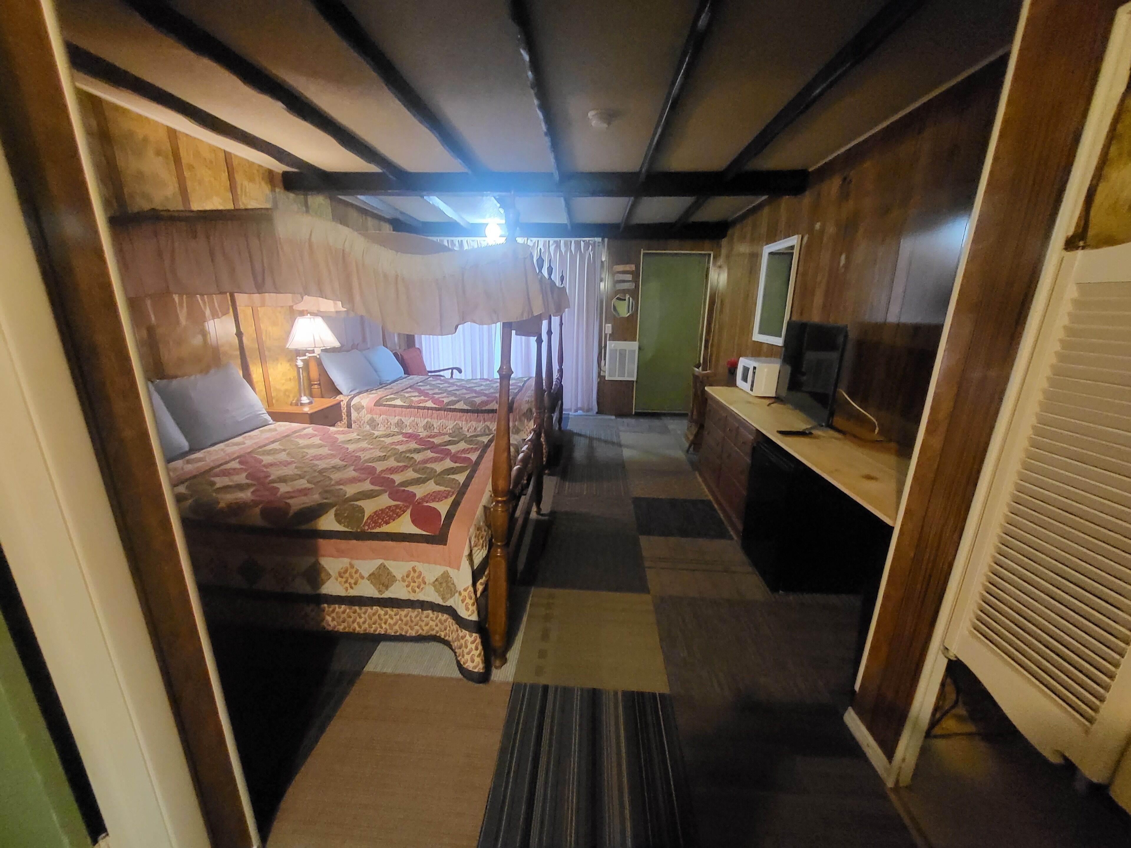 A room with two beds, a desk, a microwave, and a television.