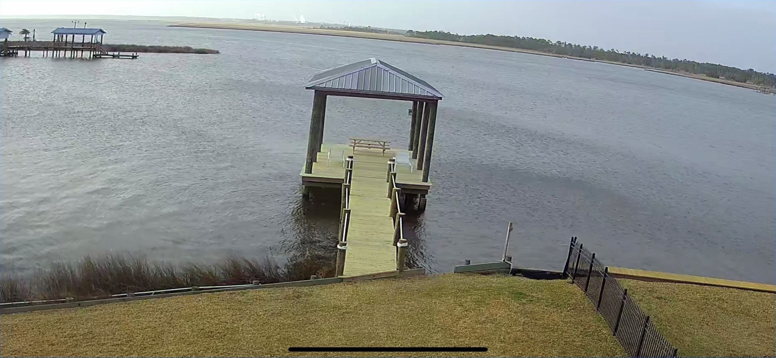 A wooden pier leading to a gazebo over water.