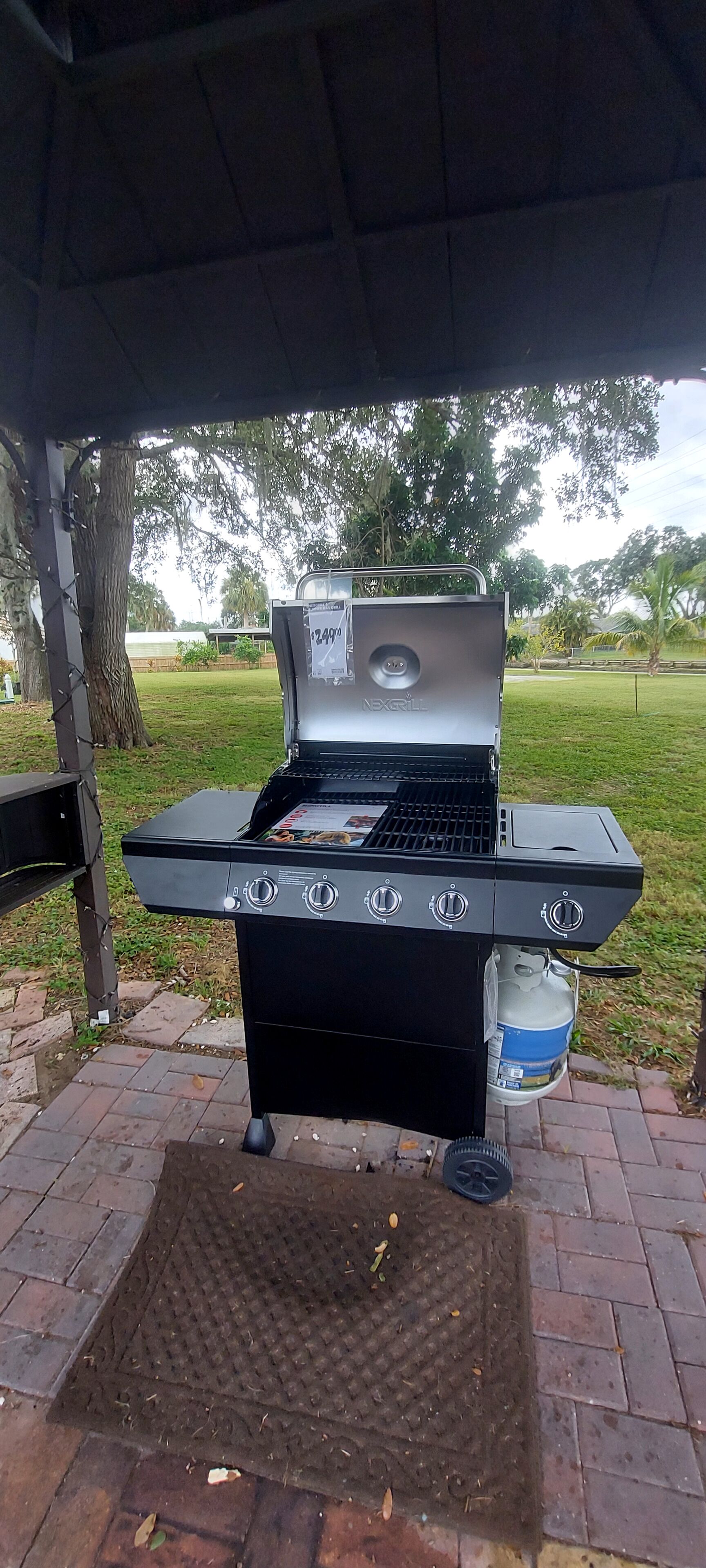 A portable grill with four burners, a digital display, and a side shelf.