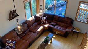 Een moderne woonkamer met een grote, hoekige modulaire bank, een houten salontafel en hanglampen.