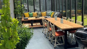 A covered patio with a wooden table, chairs, a barbecue grill, and a seating area with cushions. - Garden Cottage on Tintern Trails (New Ross)