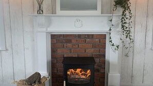 A fireplace with a brick surround, a white mantel, and a hanging plant. - Garden Cottage on Tintern Trails (New Ross)
