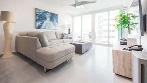 A modern living room with a sofa, a coffee table, and a TV. - OASIS 2BR/2Bath STEPS from BEACH + Parking @ ESJ (Carolina)