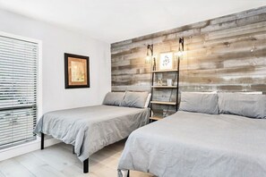 Un dormitorio con dos camas, una pared de madera, una estantería con objetos decorativos y un cuadro en la pared.