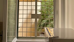 A room with a window featuring a grid pattern, a white door, and a view of a yellow building and greenery outside. - Comfy apartment with 4 double bedrooms, 4 bathrooms and a fully equipped kitchen (Roma)