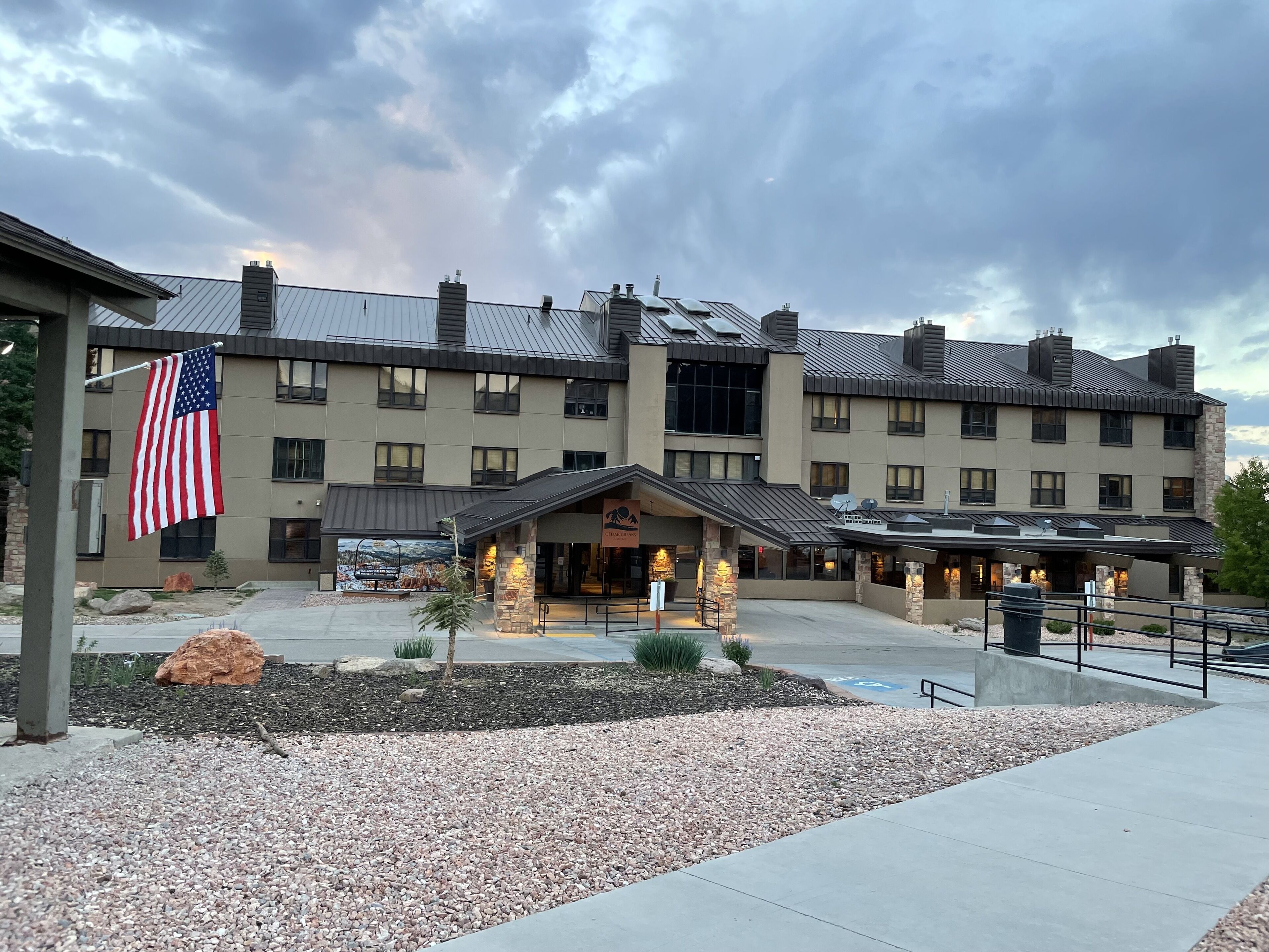A multi-story hotel with a stone facade, a covered entrance, and an American flag.