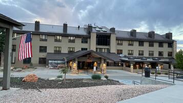 A multi-story hotel with a stone facade, a covered entrance, and an American flag.