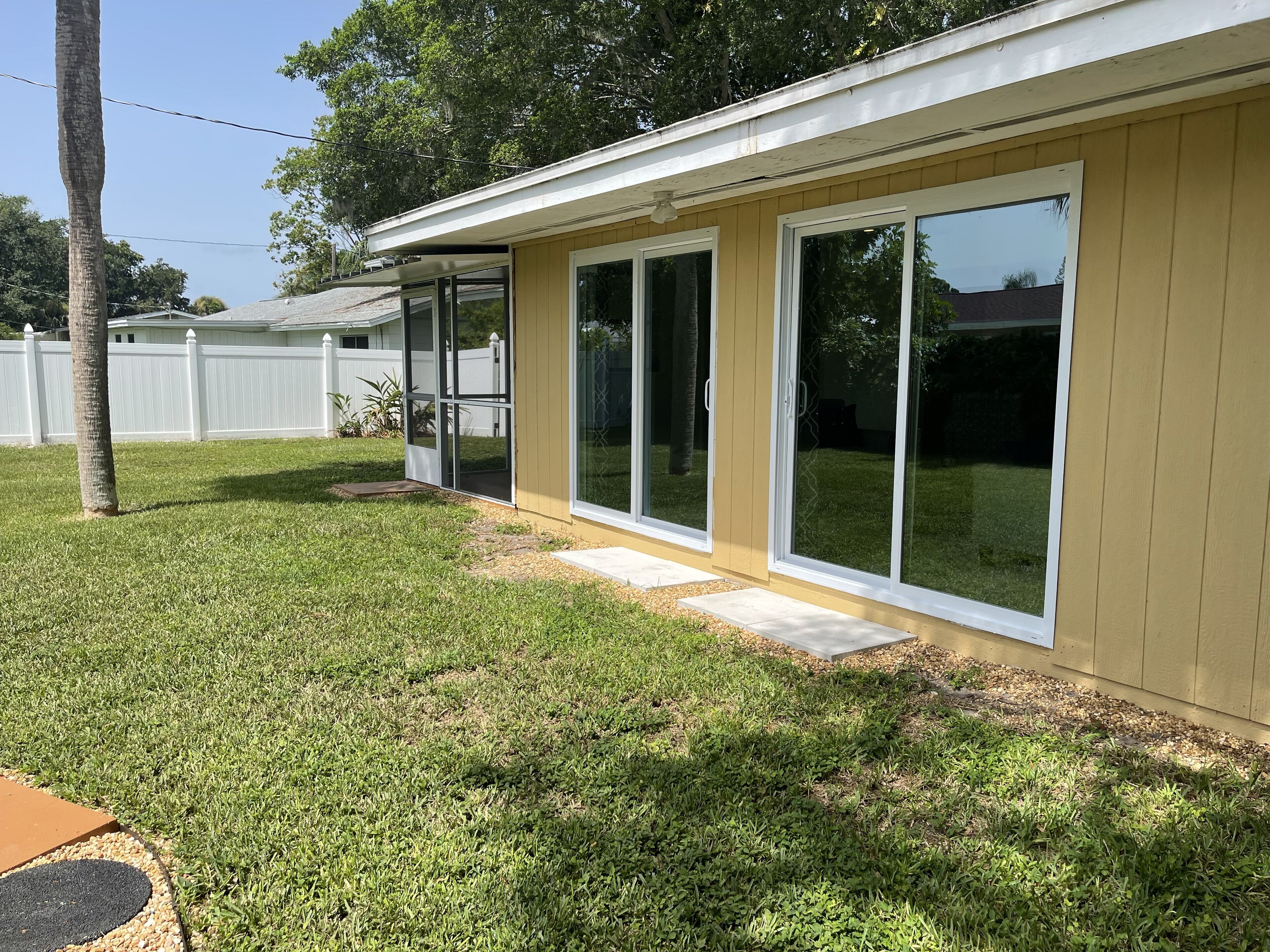 A single-story house with a covered patio, large sliding glass doors, and a well-maintained lawn.