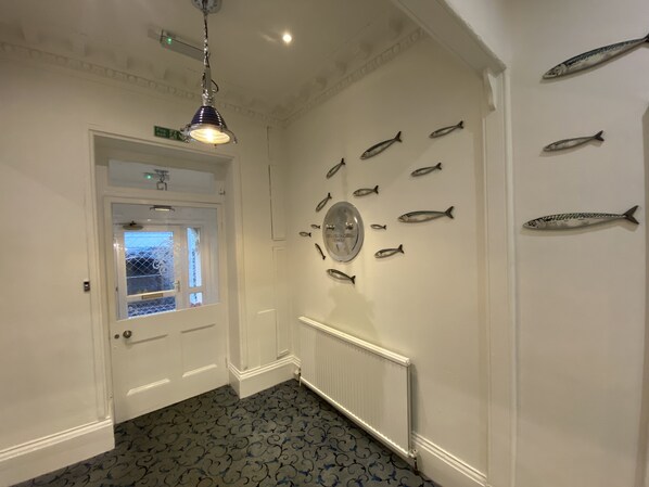 A hallway with a patterned floor, a door with a window, and a wall decorated with fish.