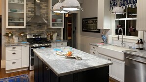 Una cocina moderna con una isla central, electrodomésticos de acero inoxidable y armarios blancos.