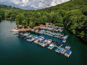A marina with numerous boats docked, surrounded by dense forest and a small building. - Pet Friendly Cabin: Hot Tub, Game Room, Fire Pits (Jasper)