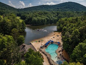 A resort with a swimming pool, beach, and boats on a lake surrounded by forested hills. - Pet Friendly Cabin: Hot Tub, Game Room, Fire Pits (Jasper)