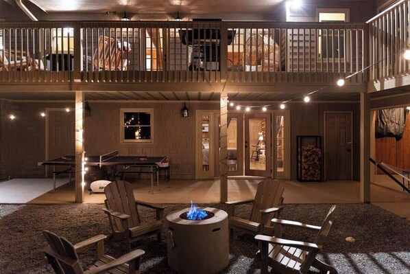 A spacious outdoor area with a fire pit, seating, and a covered balcony.
