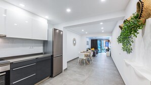 Eine moderne Küche mit weißen Schränken, einem Edelstahl-Kühlschrank und einem Essbereich mit weißem Tisch und Stühlen.