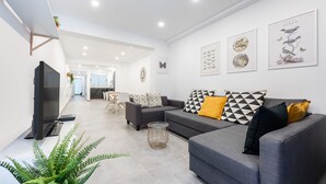 Ein modernes Wohnzimmer mit einem grauen Sofa, einem Flachbildfernseher und Kunstwerken an den Wänden.