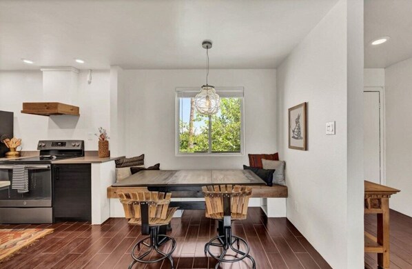 A modern kitchen with a wooden island, bar stools, and a pendant light.