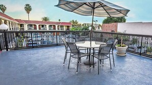 A rooftop patio with a round table and four chairs, a large umbrella, and a potted plant. - 1KNS-1 King Non Smoking (Glendale)