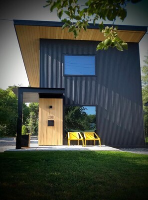 A modern two-story building with a flat roof, a large window on the upper floor, and a wooden door on the ground floor. - Unwind in the sizeable comforts of this small modern space. (Bozeman)