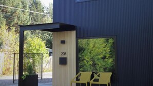 A modern building with a dark exterior, a large window, and a door marked with the number 208. - Unwind in the sizeable comforts of this small modern space. (Bozeman)