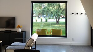 A modern living room with a large window, a flat-screen TV, and a minimalist design. - Unwind in the sizeable comforts of this small modern space. (Bozeman)