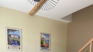A modern living room with a sofa, a dining table with chairs, a staircase, and two posters on the wall. - Little cottage (Thiouville)