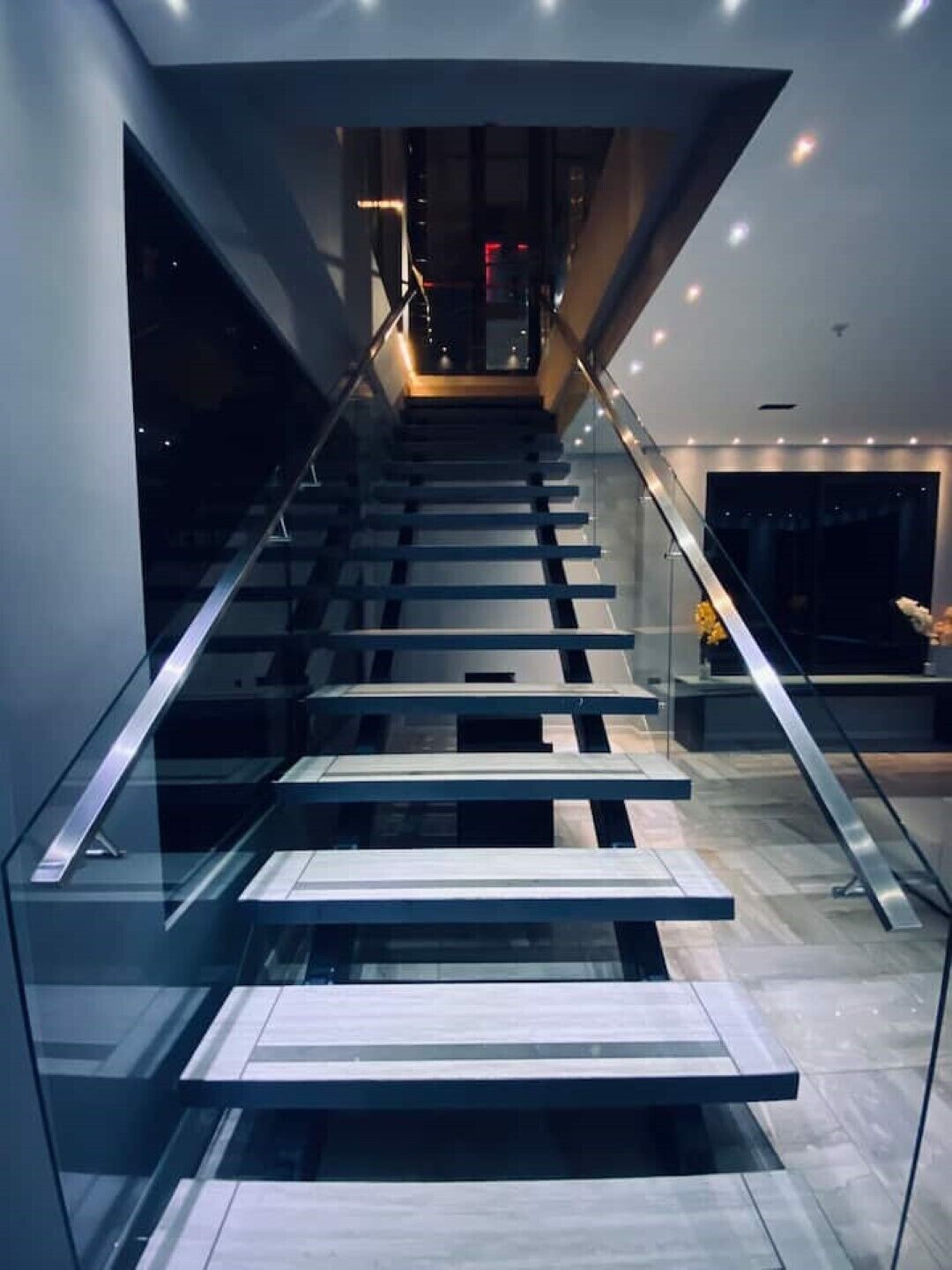 Una escalera moderna con barandillas de vidrio y un diseño minimalista.