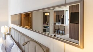Hotellihuone, jossa on suuri peili, joka heijastaa modernia kylpyhuonetta ja ruokailutilaa.