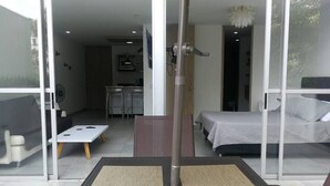 Ein modernes Zimmer mit Bett, Schreibtisch und Stuhl. Eine Glastür führt zu einem Balkon.