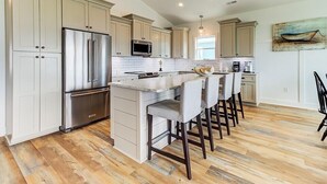 A modern kitchen with a central island, stainless steel appliances, and light-colored cabinetry.