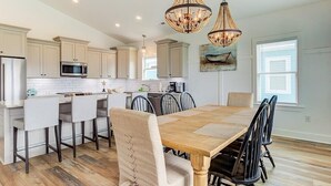 A modern kitchen with a central island, wooden flooring, and pendant lighting.