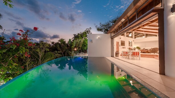 Una casa moderna con piscina, zona pranzo e garage.