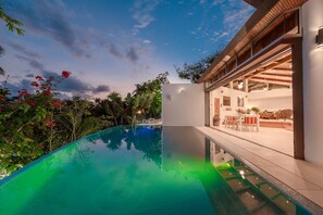 Ein modernes Haus mit Swimmingpool, Essbereich und Garage.