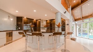 Una cucina moderna con isola centrale, sgabelli da bar in acciaio inossidabile e un'ampia finestra che offre vista all'esterno.