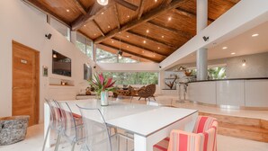 Una cucina moderna con isola centrale, sedie trasparenti e un divano a righe.