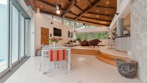 Un'ampia cucina moderna con parete in pietra, zona pranzo con tovaglia a righe e vista sull'esterno.